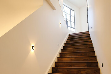 Fototapeta premium modern interior wooden staircase ascending towards bright window