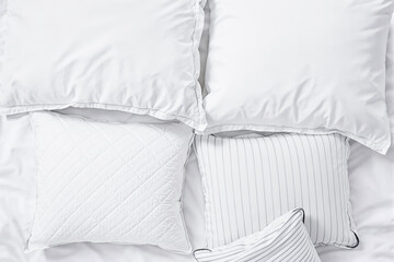 four white pillows with varied textures arranged on a bed