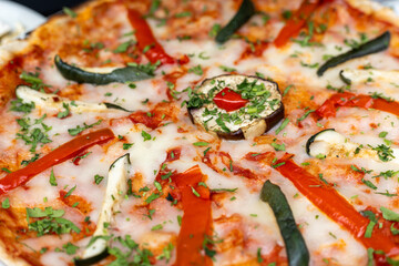 Freshly baked vegetable pizza topped with herbs, peppers, and cheese served at a cozy restaurant