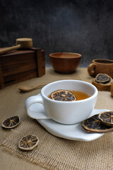 Herbal Tea with Dried Citrus in White Cup and Wooden Utensils