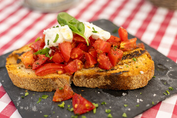 Delicious bruschetta topped with fresh tomatoes and basil served on a rustic black plate