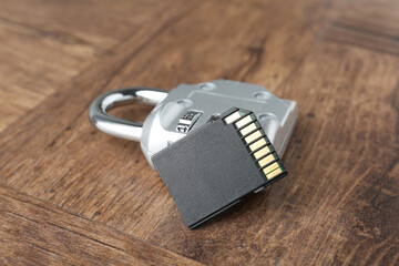 SD memory card and combination padlock on wooden table, closeup