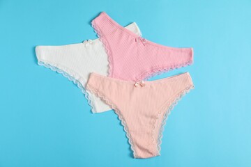 Women's underwear. Beautiful panties on light blue background, flat lay