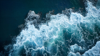Aerial view with dark ocean water and bright white seafoam. This image is ideal for illustrating natural power, marine themes, or environmental concepts.