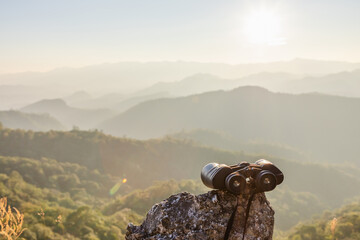 binoculars on top of rock mountain at sunset.