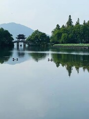 Obraz premium Symmetrical Chinese Garden Photography with Stone Bridge, Pavilion & Duck Flocks - Ink-wash Aesthetic for Cultural Tourism Promotion and Oriental Design