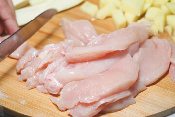Preparing fresh chicken fillets on a wooden cutting board