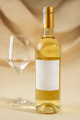 A wine glass and bottle of white wine on yellow background.
