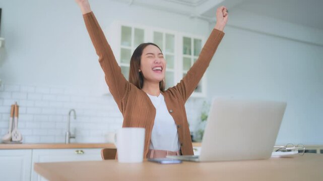 Funny euphoric young asian woman celebrating winning or getting ecommerce shopping offer on computer laptop. Excited happy girl winner looking at notebook celebrating success