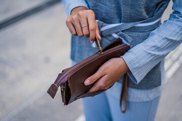 Brown leather wallet in the hands of fashionable women