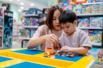 Mother and son building with plastic bricks in toy store