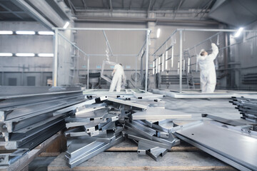 Workers in protective suit working in industrial factory preparation of structural parts for powder...