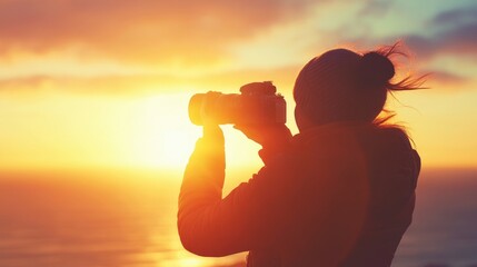 Silhouette of a person capturing a sunset over the ocean, with clouds and waves in the background