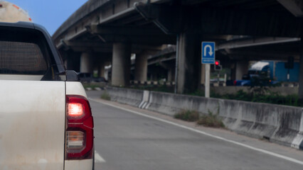 Rear side view of pickup car white color. A car slightly contaminated with mud. Stopped at a traffic light on the side of a concrete overpass.