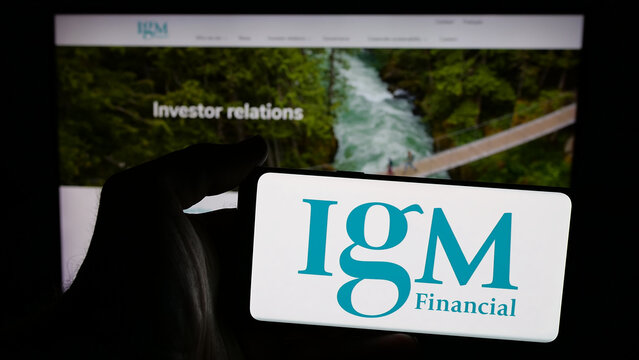 Stuttgart, Germany - 04-26-2025: Person holding mobile phone with logo of Canadian financial company IGM Financial Inc. on screen in front of web page. Focus on phone display.