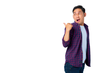 Shocked young Asian man in plaid shirt pointing thumbs at copy space, advertisement banner isolated on transparent background
