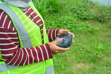 Close up of a woman flying a drone in the wild, flying a drone to check agriculture, livestock
