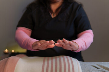 Reiki master channeling energy to patient lying on massage table, promoting relaxation and...