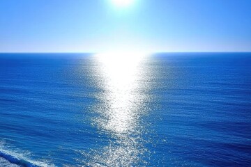 Fototapeta premium Sunlit ocean, vast expanse of blue water, bright sunlight reflecting on the surface