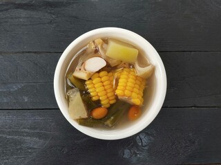 Sayur asem or Vegetables soup in bowl on black wooden table background. Indonesian typical food,...