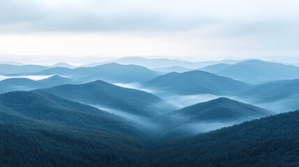 Obraz premium Serene mountain landscape shrouded in mist, showcasing layered peaks and tranquil valleys under soft cloudy skies