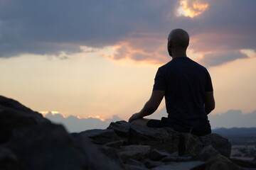 Man sitting in meditation during setting sun.