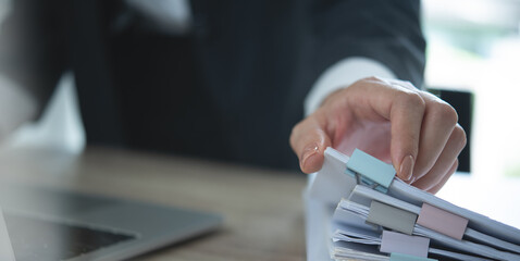 Businesswoman working with stack of paper document for searching and checking corporate files,...