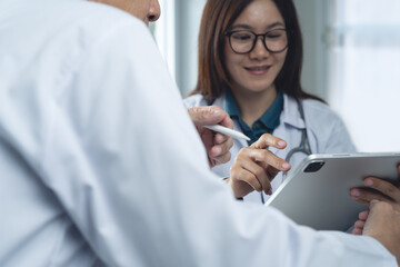 Two doctor using digital tablet and have a discussion at doctor office in hospital or medical clinic