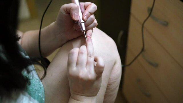 woman hands using a nail buffer on her nails after cuticle removal, showcasing a professional manicure process in slow motion