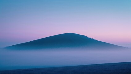 Misty dawn over a gentle, rounded hill.