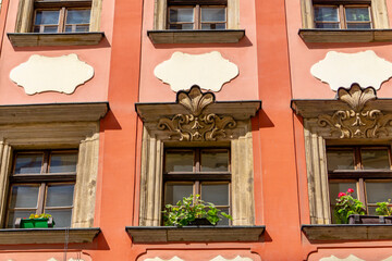 part of the facade of an old tenement house is visible, painted in an intense coral color. The...