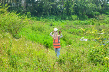 A modern corn farm manager woman carrying a book wearing a safety vest and safety helmet.