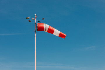 Red and White Windsock Blowing Against Clear Blue Sky