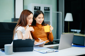 wo business women using laptop, standing and talking about analyzing documents in Teamwork Finance, Marketing