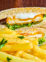 Close-up vertical shot of a sandwich and fries on a plate, capturing the detailed textures and colors of the ingredients, emphasizing the food's appeal.