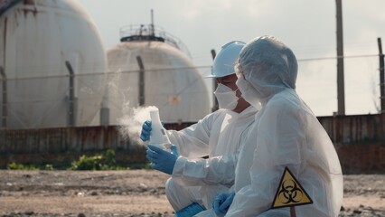 Ecologist sampling water toxic chemicals from river with test tube glass and have white smoke,...