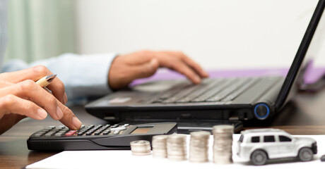 businessman using calculator and calculated car loan finance interest,at workplace, financial, refinance, accounting and banking concept	