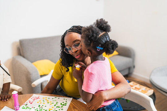 African young mother and her daughter are enjoying quality time together, painting and sharing affection in the comfort of their home