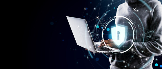Cybersecurity concept showing anonymous person using laptop with digital lock icon overlay on dark background representing data protection.