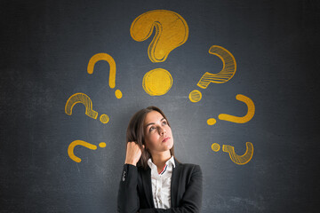 Thoughtful businesswoman surrounded by yellow question marks on dark textured background,...