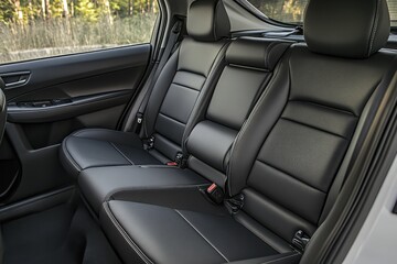 Rear interior of a vehicle, showing black leather seating.  Detailed view of comfortable back seats,  with padded support