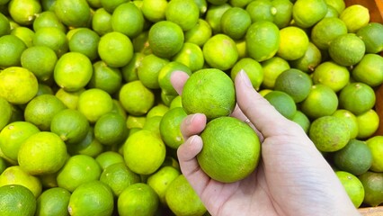Hand holding fresh limes in the market