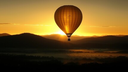 Obraz premium A majestic hot air balloon floats over mountains at sunrise or sunset