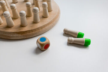 Wooden board game with colorful dice and pegs on white surface