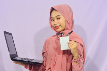 Portrait of a smart-faced Muslim female student wearing glasses, holding her laptop