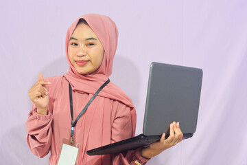 Portrait of a smart-faced Muslim female student wearing glasses, holding her laptop