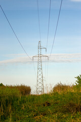 Krajobraz słup elektryczny wśród pól i łąk błękitne niebo.