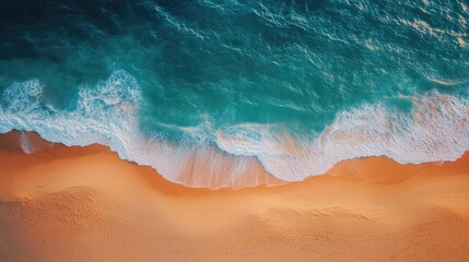 Aerial view of a sandy beach meeting turquoise ocean waves.
