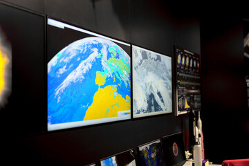Displays show detailed satellite imagery in a monitoring room for a space exploration center