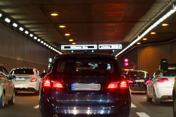 Traffic flow through urban tunnel during evening commute with illuminated signs